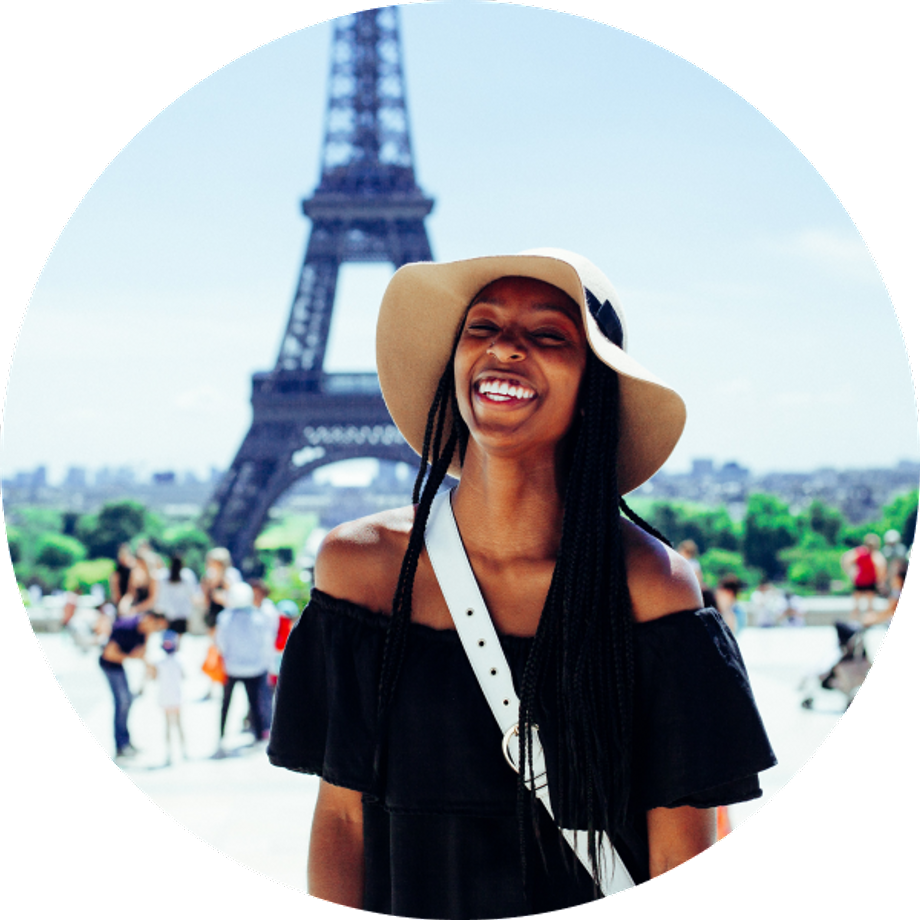 Smiling black woman with a hat in front of the Eiffel tower