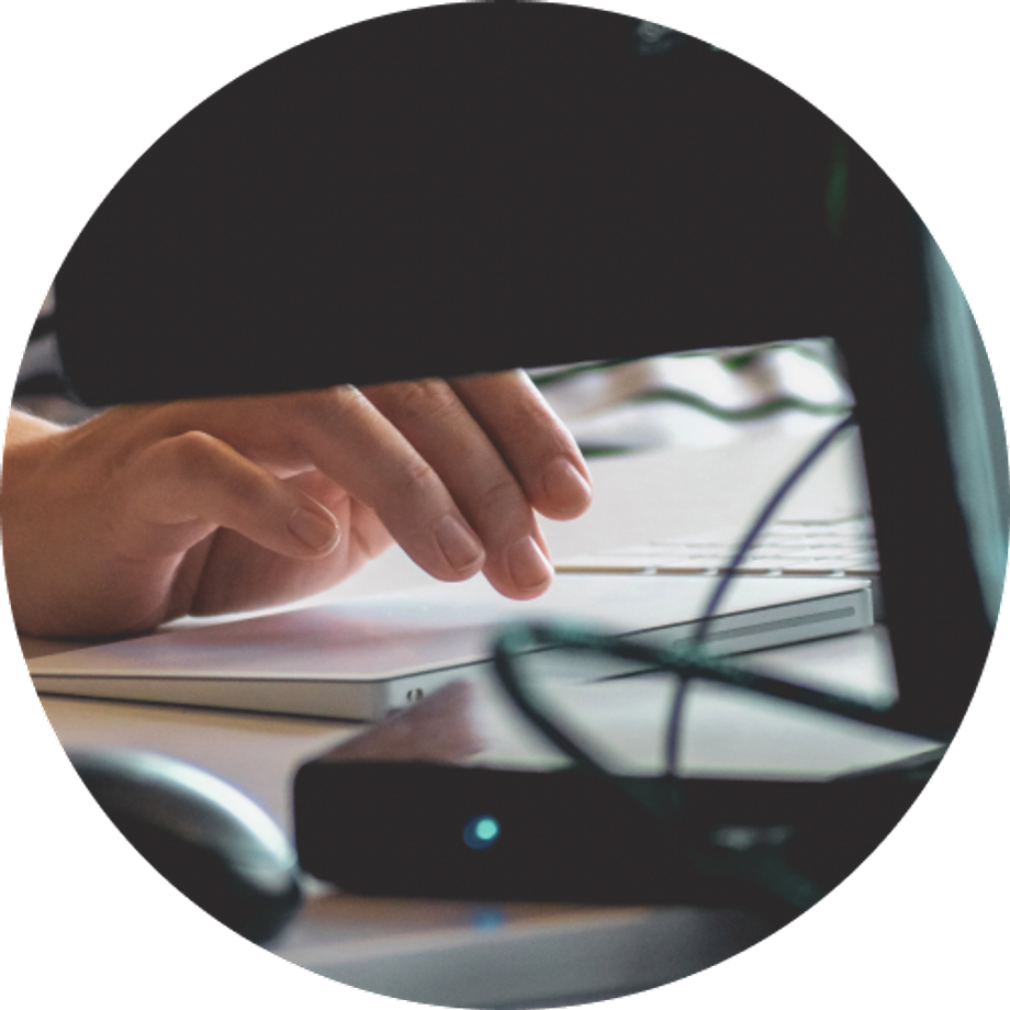 Hand using a phone at a table in front of a monitor