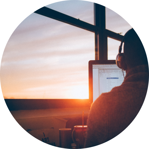 Man sitting down working on a computer with a sunrise background